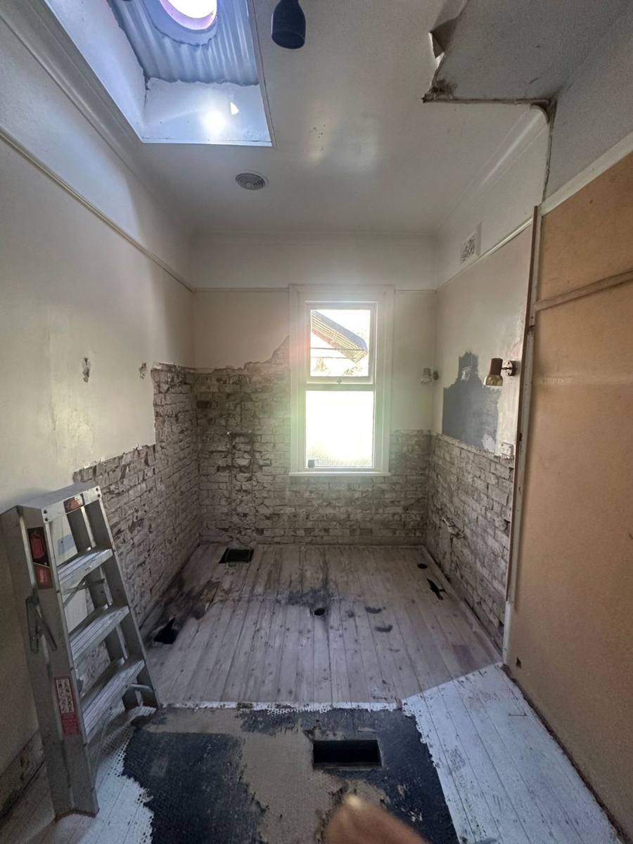 Bathroom stripped back to brick walls and floor boards during a renovation