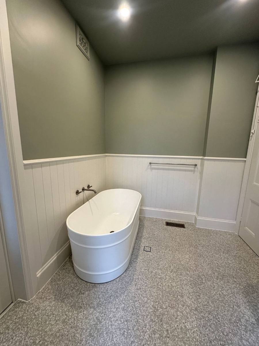Freestanding bath with floor-mounted spout against white wall panelling