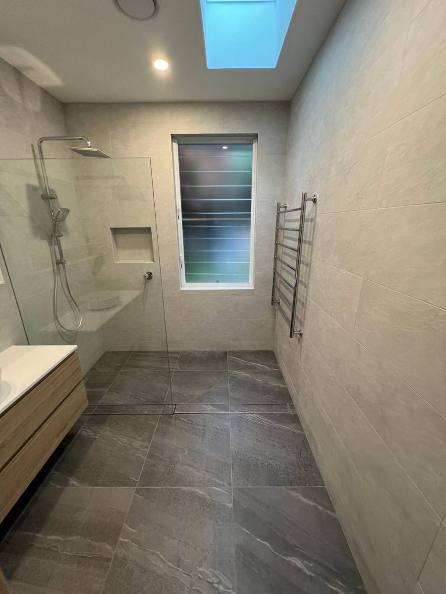 Walk-in shower with frameless glass, wall niche and large grey floor tiles