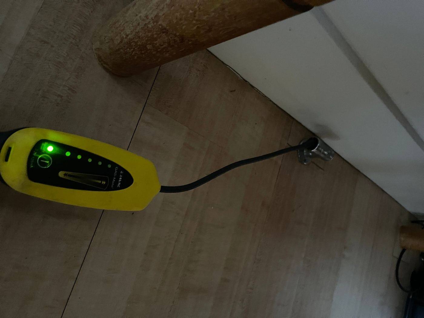 Gas leak detector held at a gas bayonet fitting near the floor