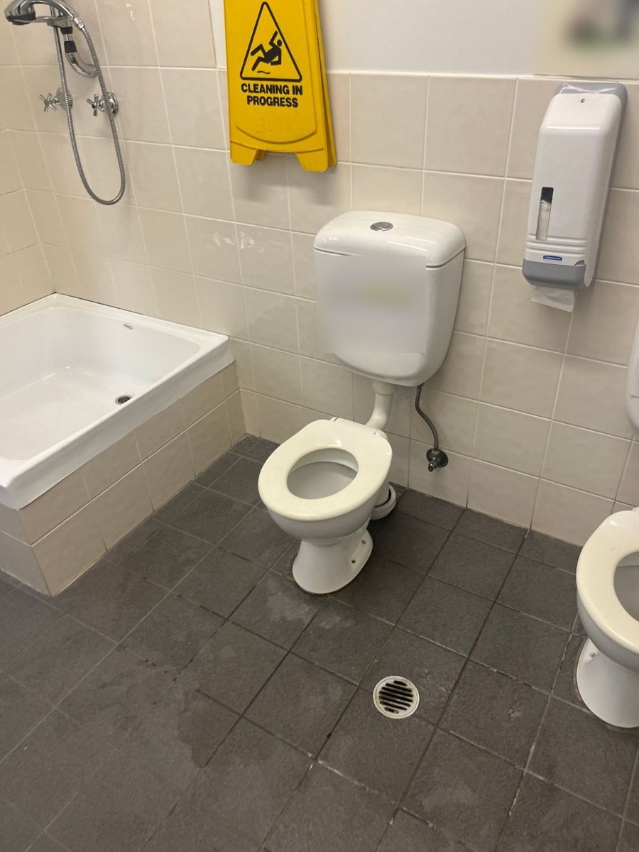 Workplace toilet with a wet floor sign, before the repair