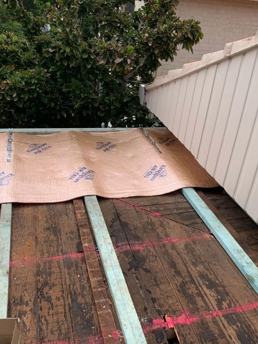 Insulation blanket being laid over new roof battens before the sheets go on