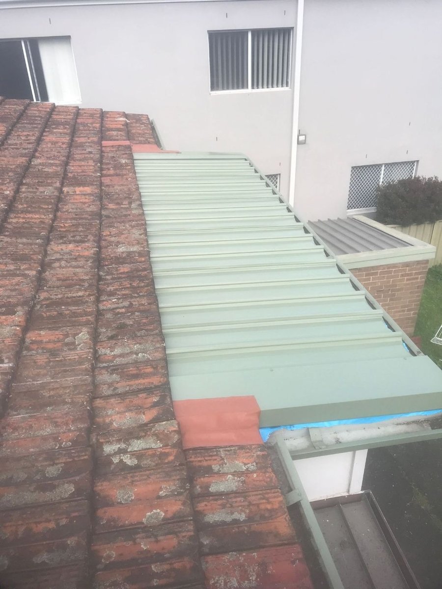 New Colorbond roof sheets and flashing beside an old tiled roof
