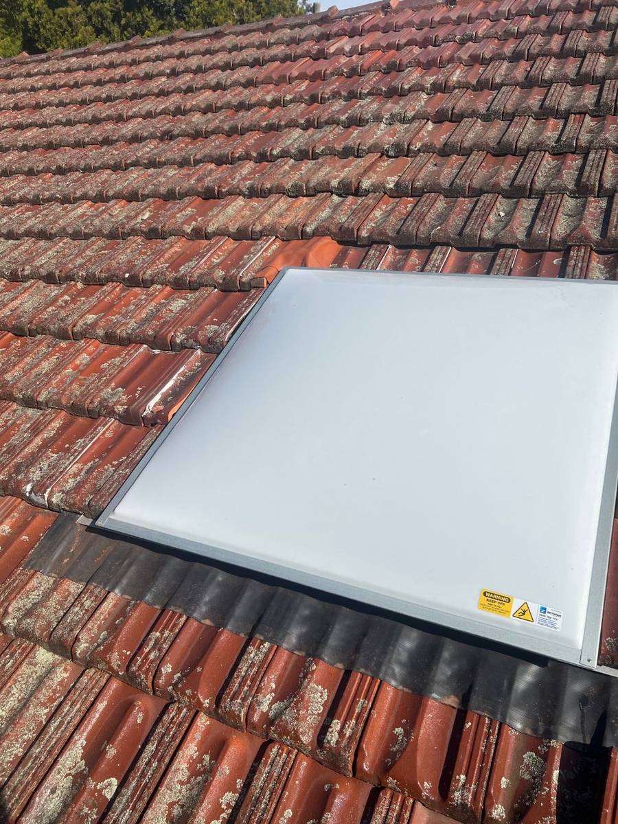 New skylight fitted into a terracotta tiled roof with new flashing below it