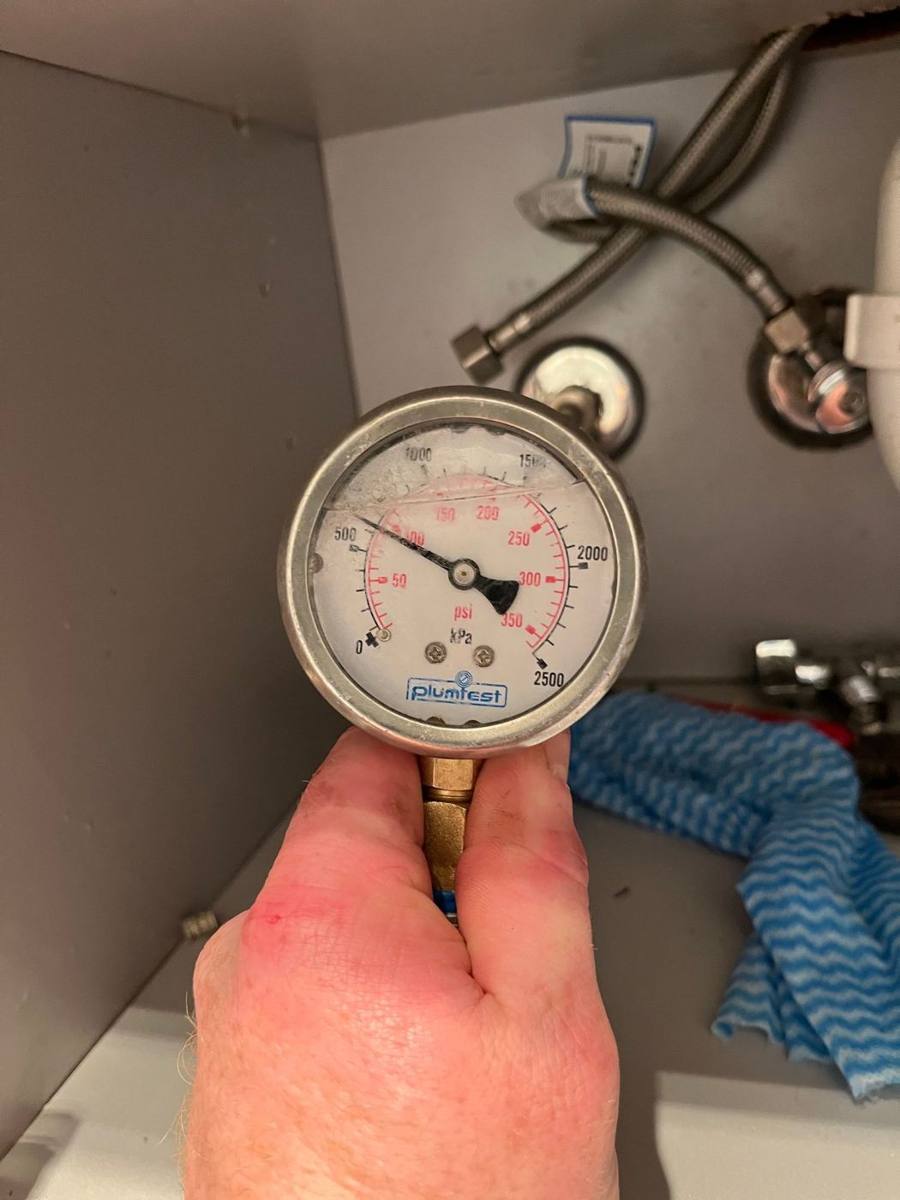 Pressure gauge connected to the water supply under a unit's kitchen sink