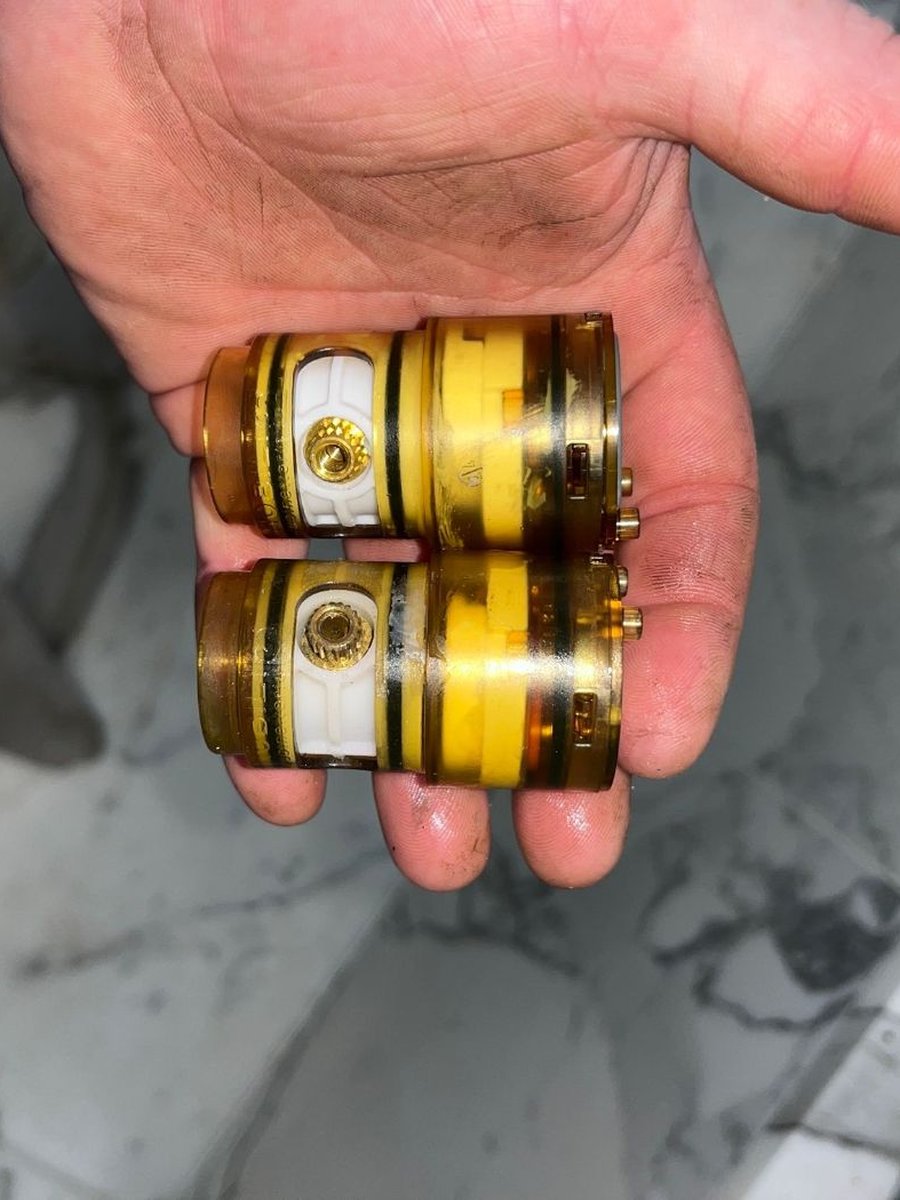 Two worn shower mixer cartridges held in a hand
