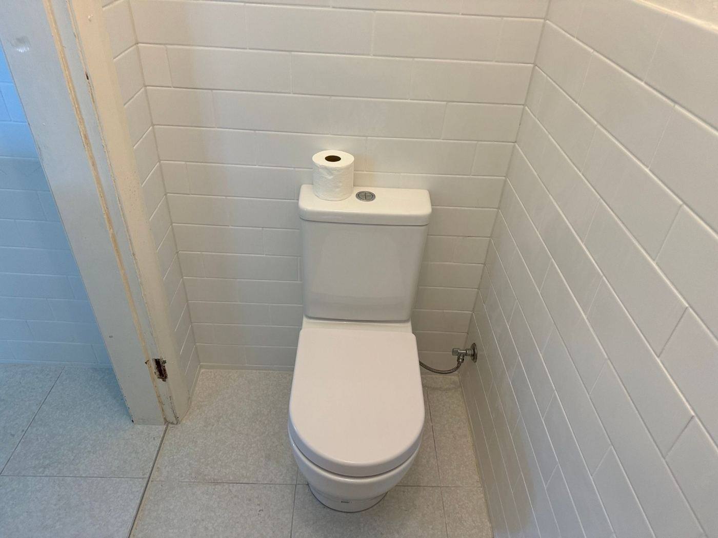 New close-coupled toilet installed in a tiled bathroom