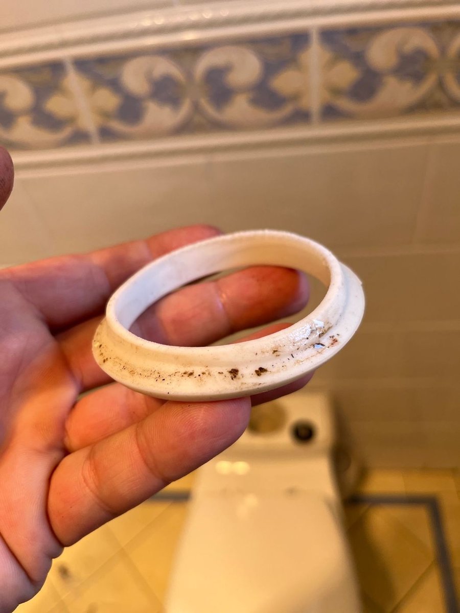 Old toilet seal held in a hand, stained where water had been getting past