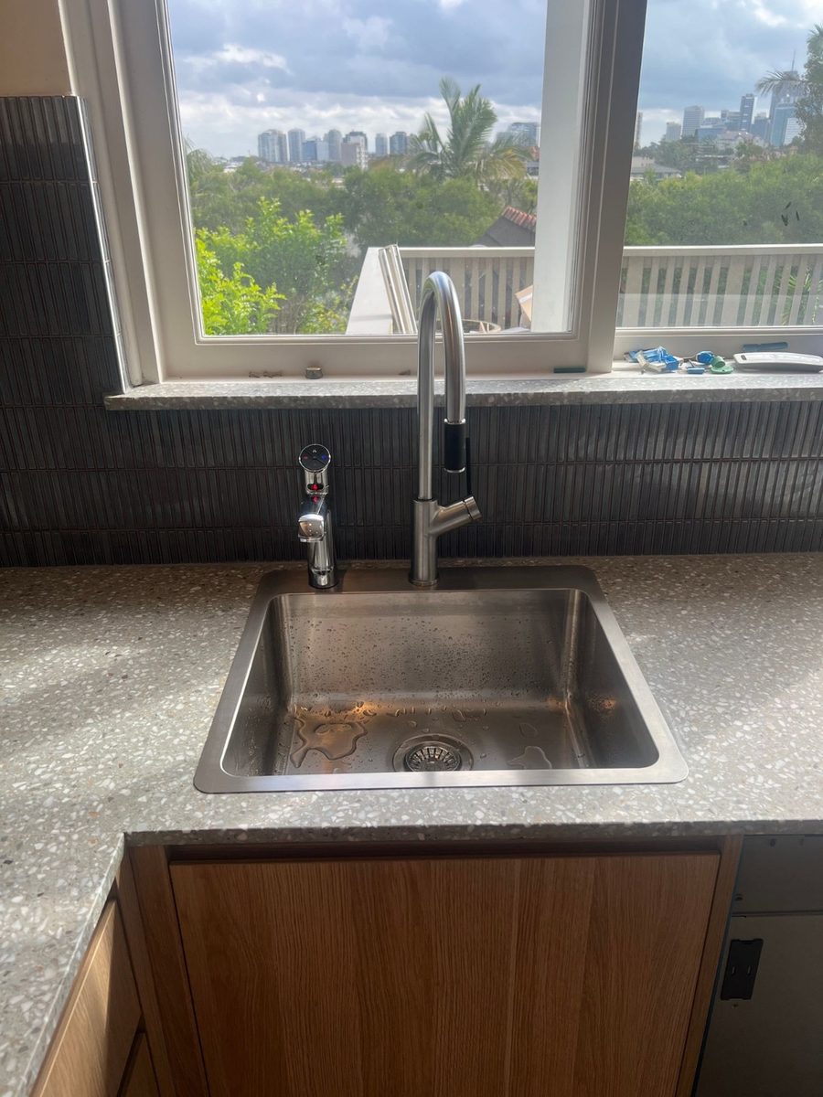 A sink and filtered water tap with a city skyline view