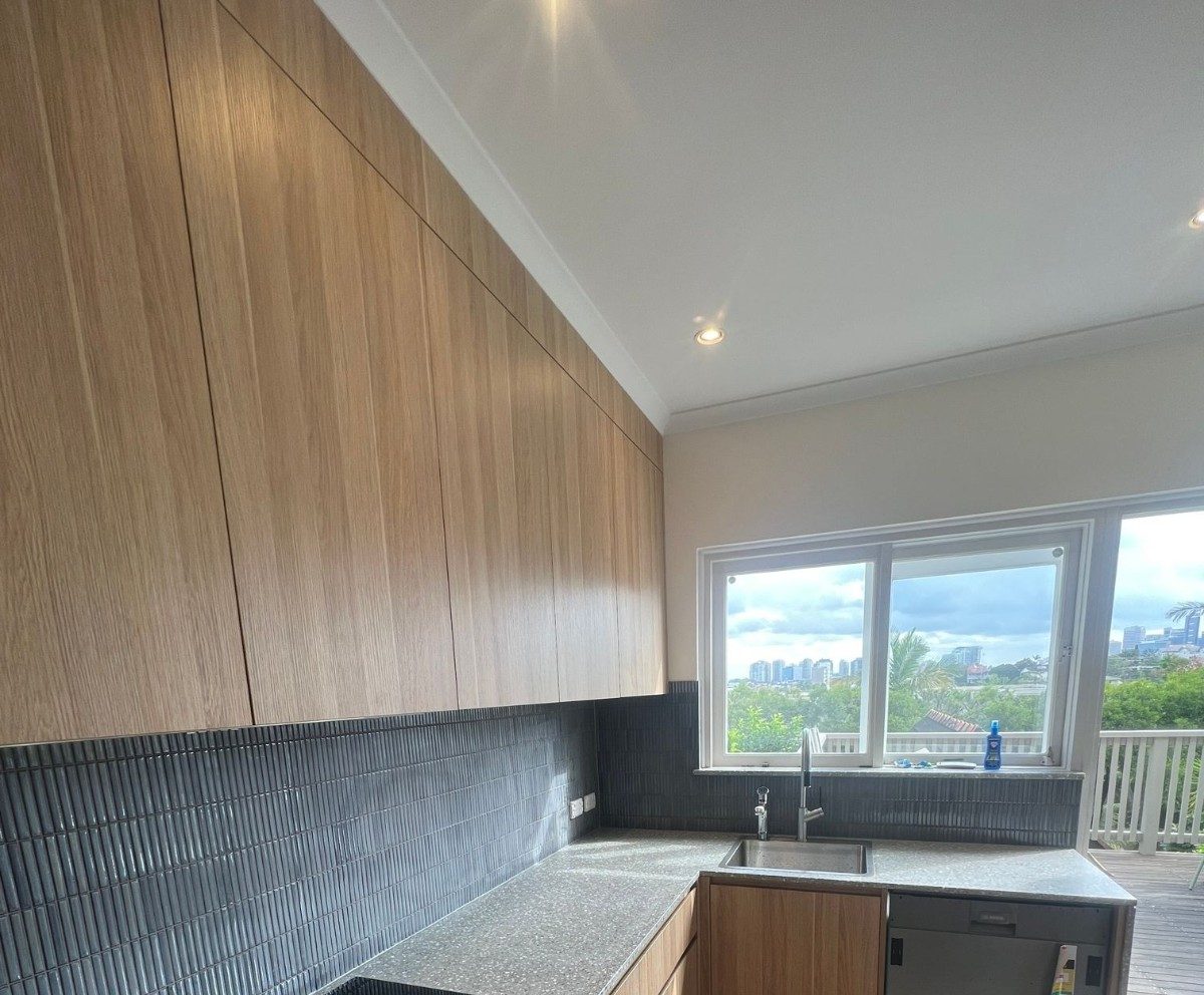 A new timber kitchen with a terrazzo bench and a city view